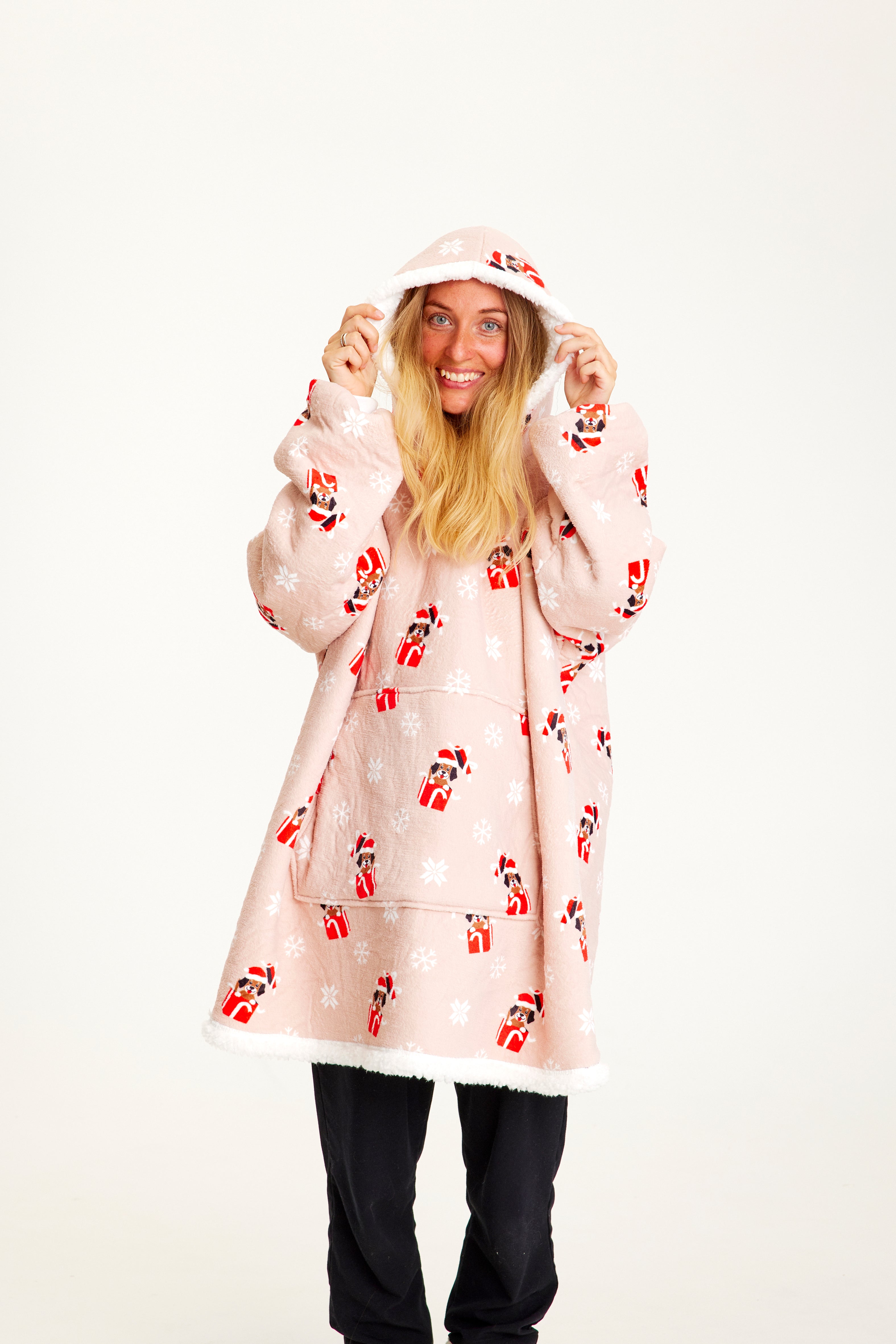 Eine Frau trägt einen rosa Weihnachts-Kapuzenpulli mit Hunden darauf.